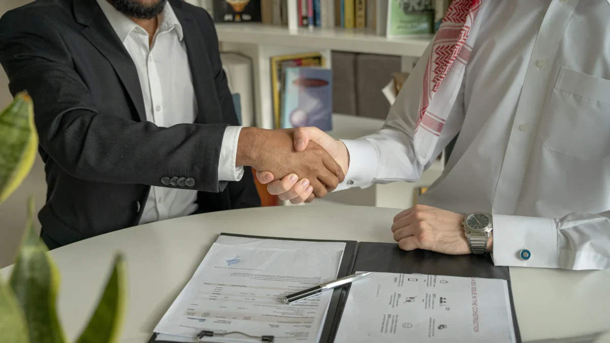 Business partners shaking hands over a signed agreement