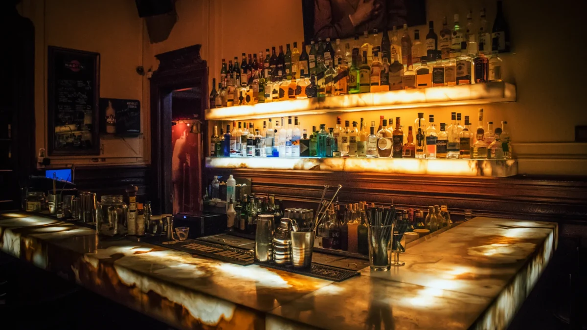 Bar counter with backlit shelves of bottles