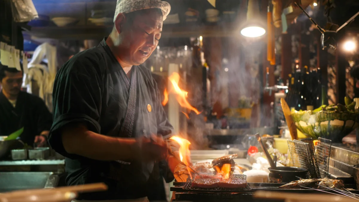 Cook stir-frying with a flaming wok at a food stall