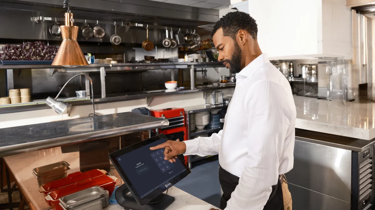 Staff member using an order terminal at a restaurant kitchen counter