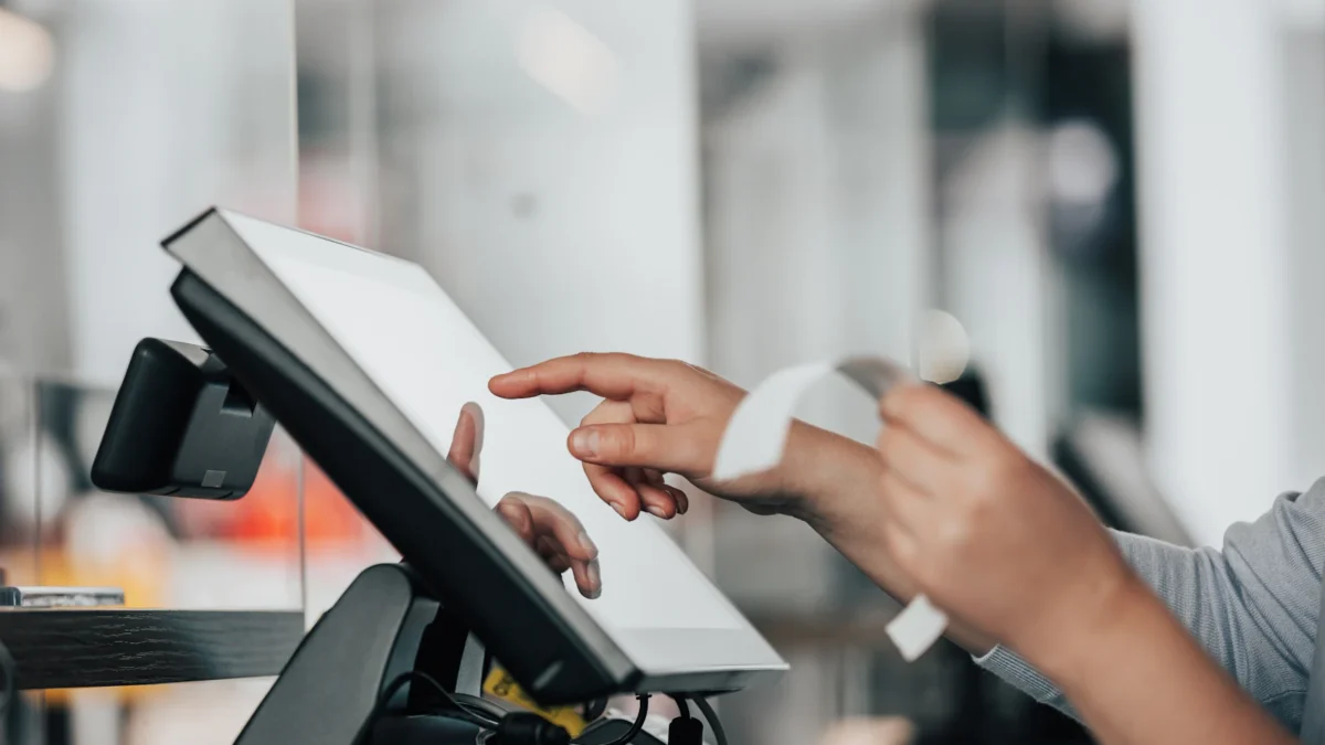 Cashier using a touchscreen POS terminal at a counter